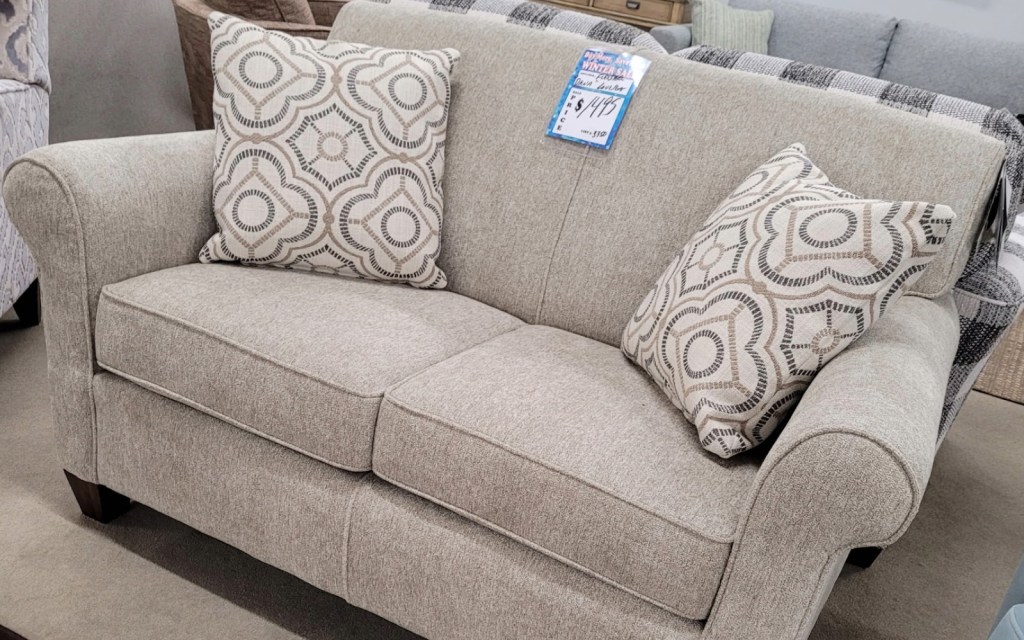 Light gray fabric loveseat with rolled arms and patterned accent pillows on display at Meyers Furniture in Mendota IL