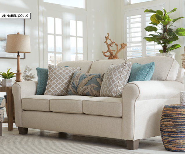 Light neutral fabric sofa with patterned accent pillows styled in a bright, sunlit living room