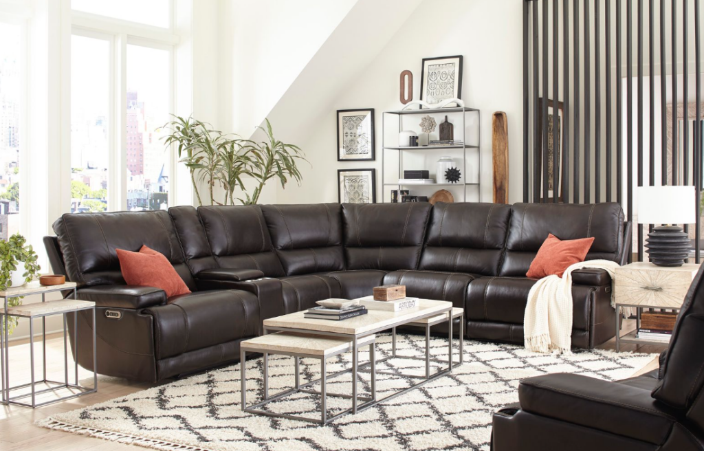 Dark leather Parker House sectional styled in a bright living room with pillows, tables, plants, and wall decor.