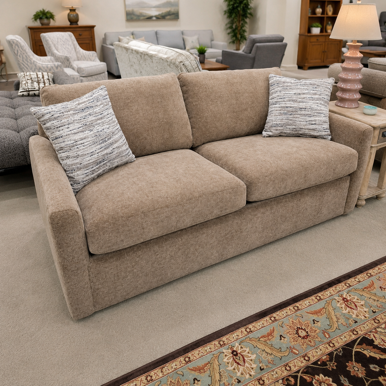 Tan sleeper sofa with neutral fabric and patterned pillows displayed in the Meyers Furniture showroom.